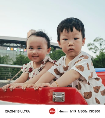 一个年轻男孩和一个小女孩骑着一辆红色的玩具车 一个小孩子坐在车顶上。