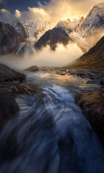 a river flowing through a valley with mountains in