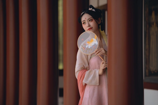 一位穿着日本传统和服的年轻女子站在寺庙里 手里拿着扇子 站在一面镜子前。