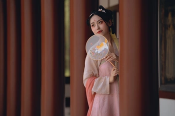 一位穿着日本传统和服的年轻女子站在寺庙里 手里拿着扇子 站在一面镜子前。