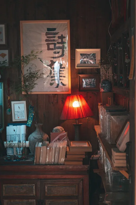 一个带有书桌、书籍、红灯和墙上挂着图片的房间