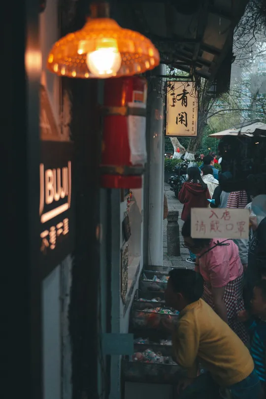 一条狭窄的街道上有一群人 带着伞。