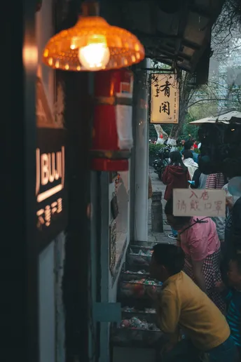 一条狭窄的街道上有一群人 带着伞。