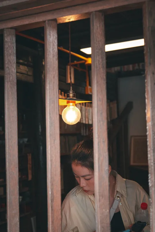 一个人在一个有栏杆窗户的房间里读书 一个妇女正在看她的手机。