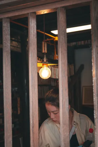 一个人在一个有栏杆窗户的房间里读书 一个妇女正在看她的手机。