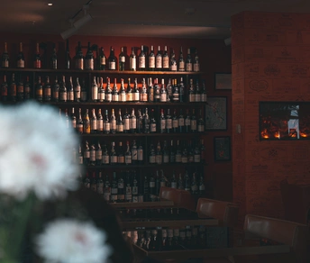 一个带有酒吧和装满葡萄酒瓶的架子以及插满鲜花的花瓶的餐厅。