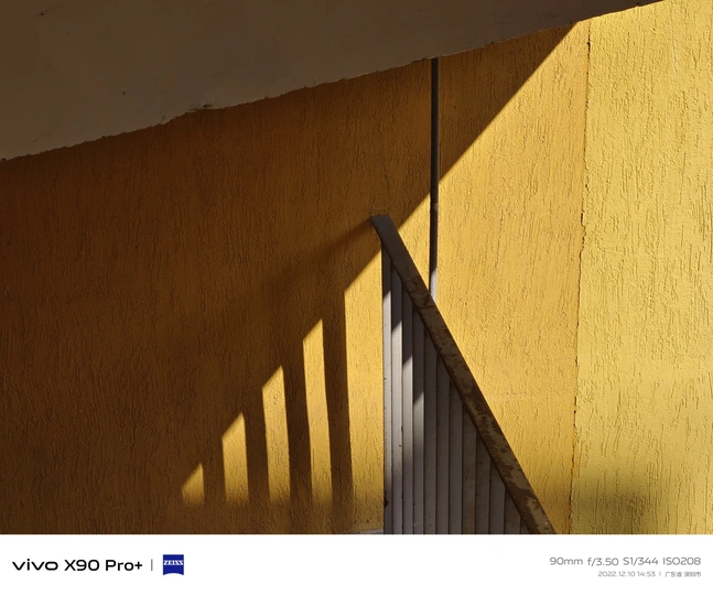 黄色墙壁的角落 楼梯和窗户在房屋的墙壁上投下阴影。