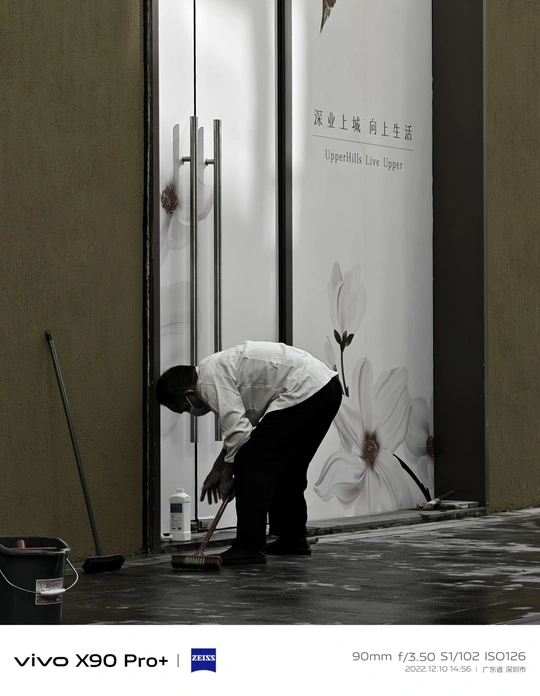 一位男士正在清洗一栋楼房旁边的白色花朵的地面。