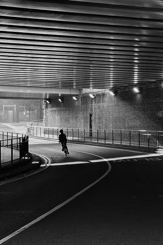 一张黑白照片 夜晚 隧道 一个人在公路上走。