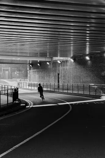 一张黑白照片 夜晚 隧道 一个人在公路上走。