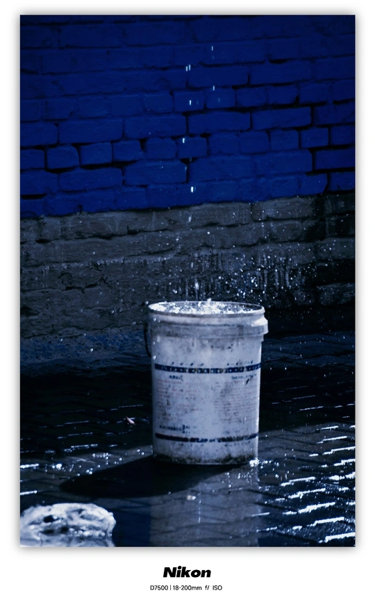 一桶水在蓝色砖墙前