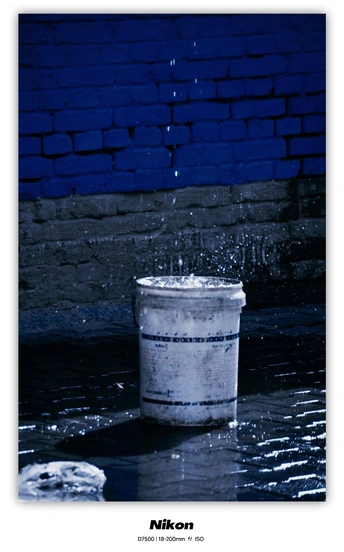 一桶水在蓝色砖墙前