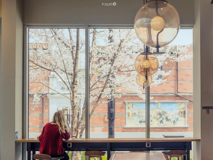 一个人坐在桌子旁 透过一扇大窗户向外看。