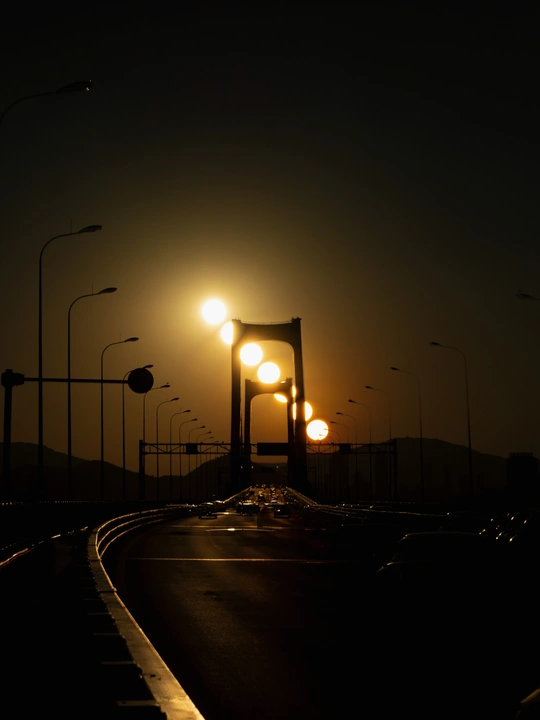 夜晚的公路上有汽车、街灯和一座桥。