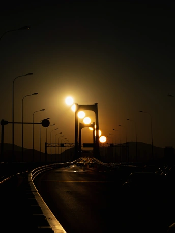 夜晚的公路上有汽车、街灯和一座桥。