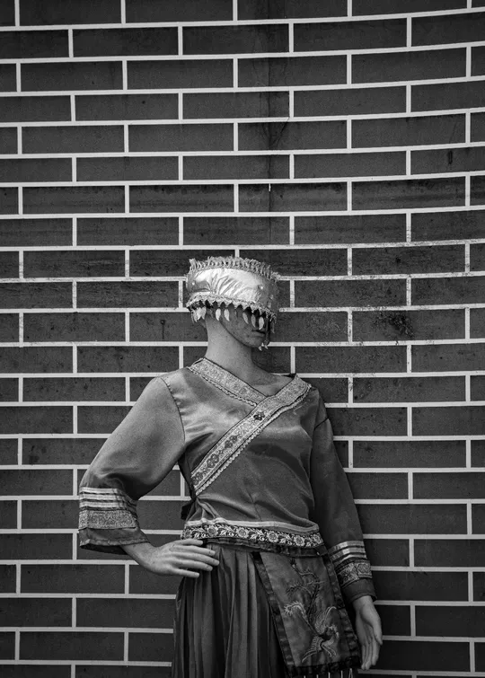 一位穿着服装的黑白色女性靠在砖墙上