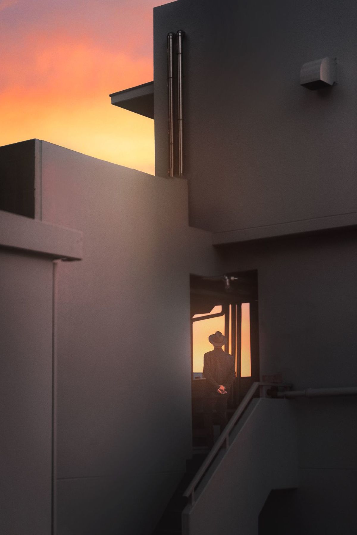 一个人在日落时通过建筑物的窗户
