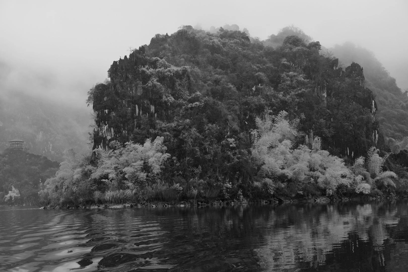 湖中小岛的黑白照片 背景有树木和山脉