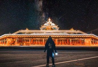 一个人站在停车场 一座夜晚被照亮的大楼。