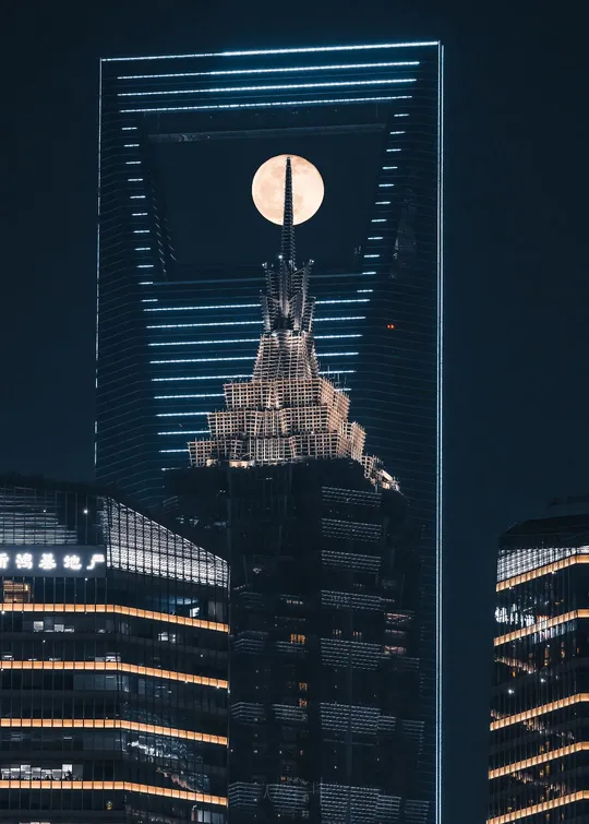 城市中高楼后面满月升起