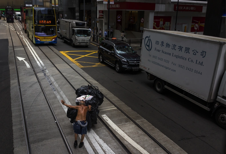 一个人背着书包 提着行李袋 走下繁忙的城市街道的人行道。