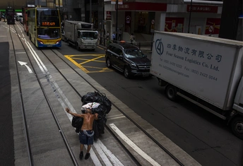 一个人背着书包 提着行李袋 走下繁忙的城市街道的人行道。