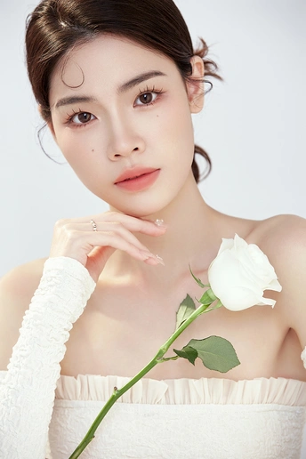 一位拥有完美肌肤和妆容的美女手持白色玫瑰的肖像