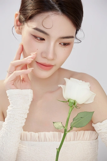 一位年轻女子拥有美丽的皮肤和化妆品 手中握着一朵白玫瑰。