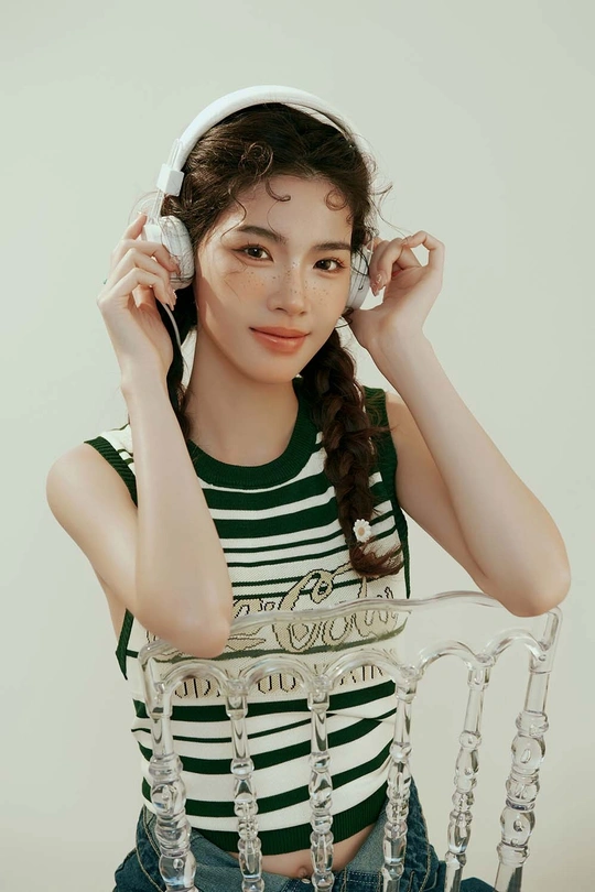 一个年轻女子穿着条纹白色衬衫 坐在那里 戴着耳机