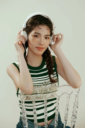 一个年轻女子穿着条纹白色衬衫 坐在那里 戴着耳机