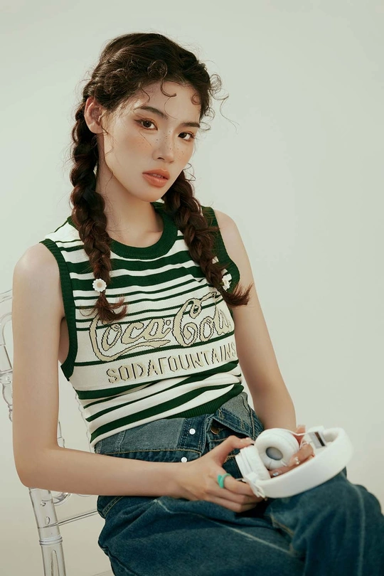 一个年轻女子坐在椅子上 手里拿着一个Wii遥控器。