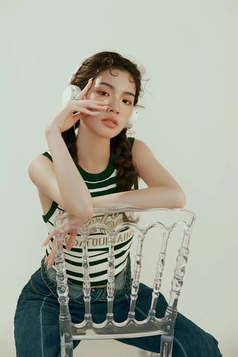 一个年轻女子坐在椅子上 脸靠近牛仔裤 摆姿势。