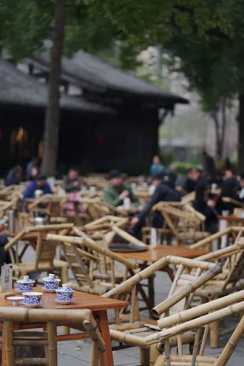 很多人坐在户外的桌子旁边。