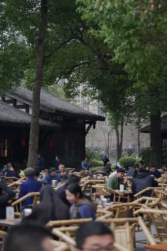 人们坐在户外桌子旁 带着伞