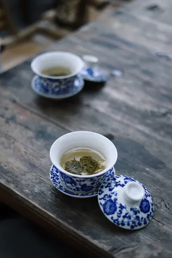 一个蓝色的茶壶和一杯绿茶 放在木桌上