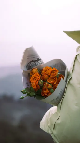 手拿一束橙色玫瑰花的男人