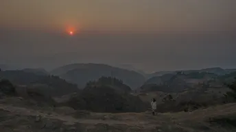 日落或日出时 山谷上有人站在山顶 太阳在天空中落下。
