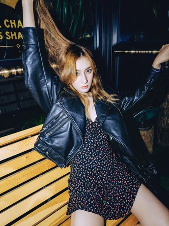 一个穿着黑色连衣裙和高筒靴的年轻女子坐在木凳上