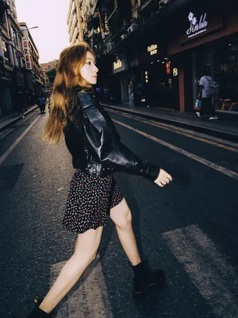 一个穿黑色皮夹克的女人走在马路中央的路上