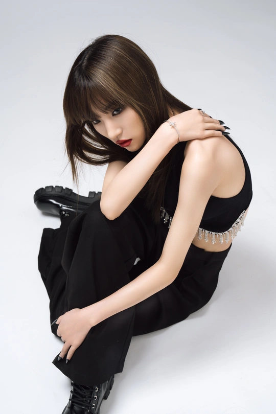 美丽的年轻女子穿着黑色连衣裙和靴子坐在地板上