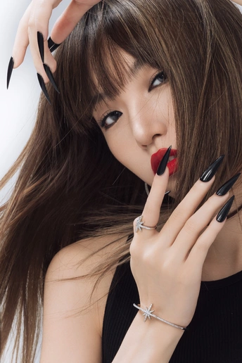 一位穿着黑色妆容和红色口红的年轻女子 双手放在指甲上 嘴唇微张。