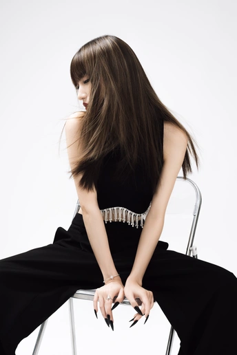 一个穿着黑色连衣裙 长发飘飘的年轻女子坐在黑色和白色椅子上的女子