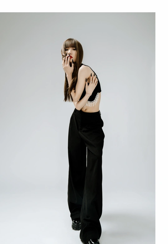 一位穿着黑色连衣裙和黑色裤子的年轻女子站立并手持手机