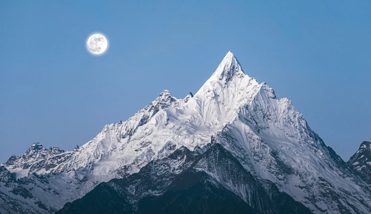 山脉上的积雪峰顶上升起了满月。