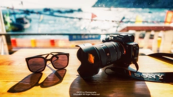 一张相机的照片 上面放着一副太阳镜 放在木桌上