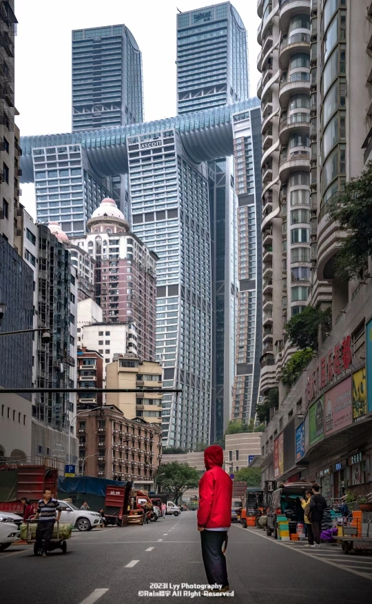 一位穿着红色夹克的女人在大城市的街道上走过 前面有高大的建筑。