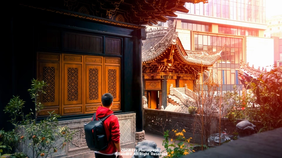 一位穿红衣服的男子站在中国寺庙前 眺望着城市。