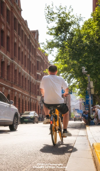 一位骑着黄色自行车沿着停满车的城市街道行驶的男子