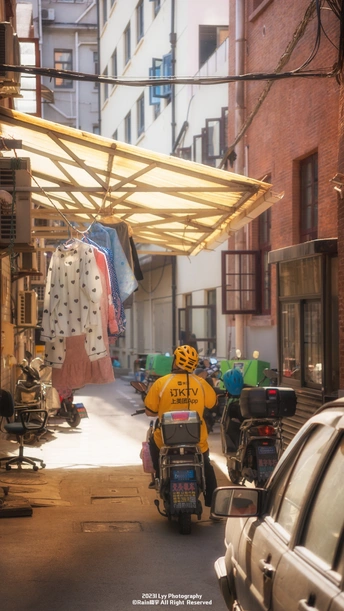 一条狭窄的巷子 停满了汽车和摩托车 停在建筑物的侧面 下面有遮阳篷。