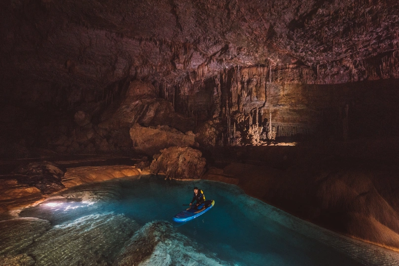 一个人在蓝色水的大洞穴中的船上
